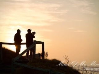 Two people silhouetted at coastal lookout during sunrise in Australia