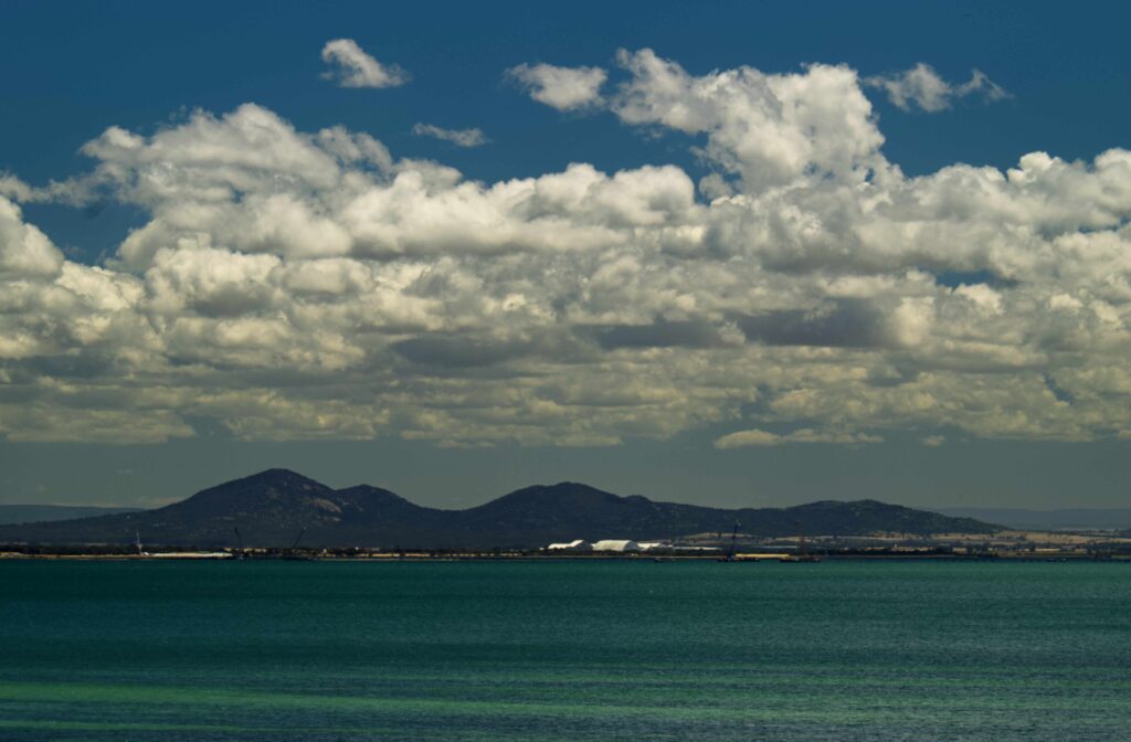 Clouds drift above the You Yang Ranges viewed from Clifton Springs across calm turquoise water.
